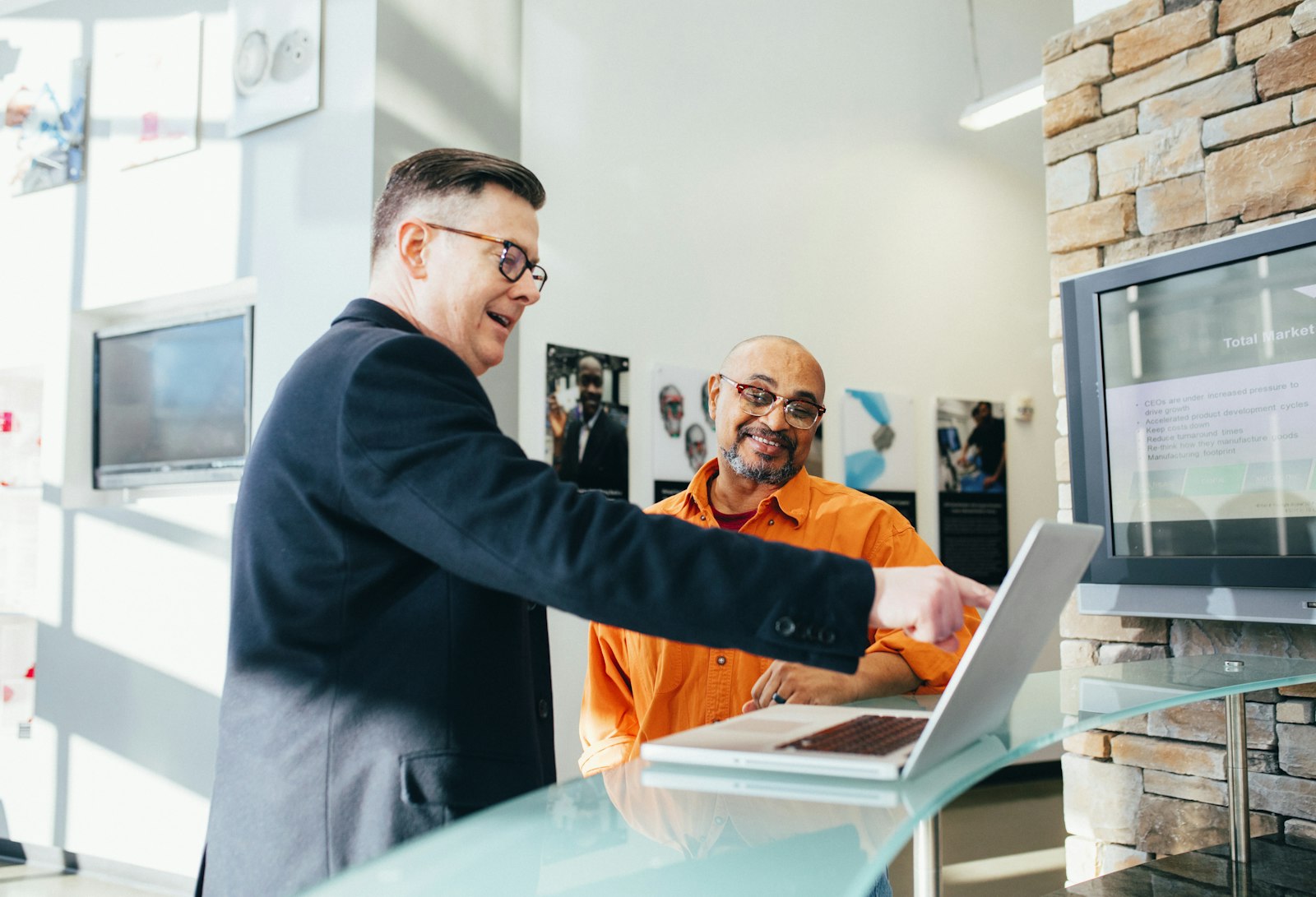 Two teammates leaning over a laptop while discussing customer support work